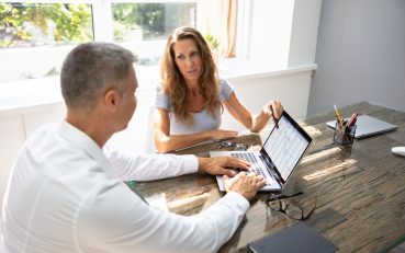 Two,Mature,Businesspeople,Analyzing,Gantt,Chart,On,Laptop,Over,Desk